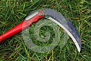 The vibrant green grass with manual small scythe. Gardening with sharp razor tool.