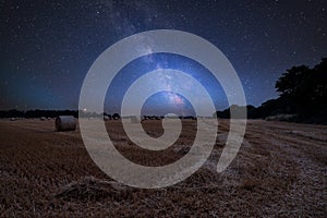 Vibrant Milky Way composite image over landscape of field of hay