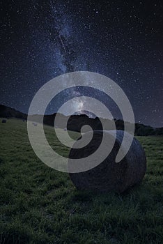 Vibrant Milky Way composite image over landscape of Summer countryside of field with hay bales