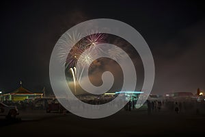 a vibrant night scene at a fairground, illuminated by multiple fireworks, with a crowd of people and colorful tents, ai generative
