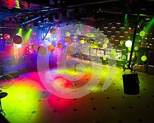 Vibrant nightclub dance floor with colorful lights and reflective balloons overhead, an inviting space for music and dance