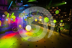 Vibrant nightclub dance floor with colorful lights and reflective balloons overhead, an inviting space for music and dance