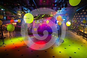 Vibrant nightclub dance floor with colorful lights and reflective balloons overhead, an inviting space for music and dance