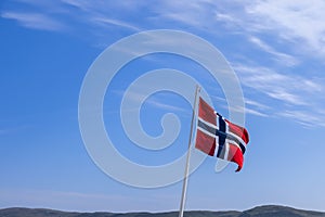 A vibrant Norwegian flag unfurling against a cerulean sky on a sunlit summer day