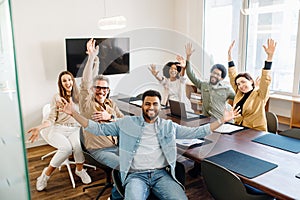 A vibrant office team celebrates with raised hands and beaming smiles