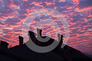 Vibrant orange clouds over rooftop chimneys