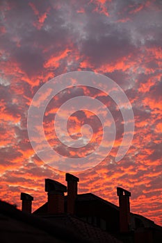 Vibrant orange clouds over rooftop chimneys
