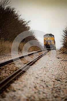 Vibrant orange passenger train traveling along a scenic countryside train track