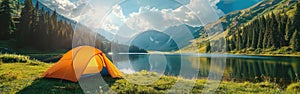 A vibrant orange tent is pitched on the green grass near a tranquil lake on a beautiful summer day