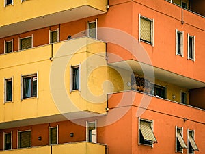 Vibrant orange and yellow exterior of a modern apartment building with multiple balconies