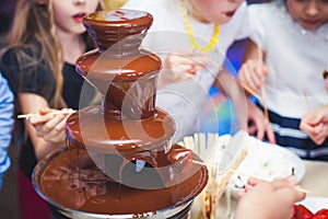Vibrant Picture of Chocolate Fountain Fontain on childen kids birthday party with a kids playing around and marshmallows and fruit photo