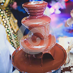 Vibrant Picture of Chocolate Fountain Fontain on childen kids birthday party with a kids playing around and marshmallows and fruit