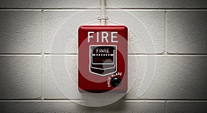 Red fire alarm pull station on a white brick wall in a building or corridor