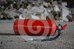 Vibrant red fire extinguisher situated among a pile of grey and white stones