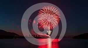 Vibrant Red Fireworks Exploding Over a Calm Lake at Night