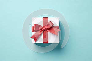 Vibrant red gift box decorated with white satin ribbon and bow, against a pastel blue backdrop