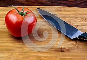 A vibrant ripe red beef steak tomatoon a cutting board with a ch