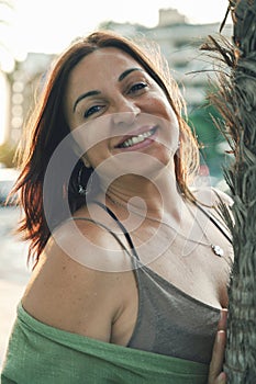 Vibrant Spirit: Portrait of a smiling brunette woman leaning against a palm tree