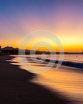 A vibrant sunrise with light reflecting in waves on the coastline of Cabo San Lucas