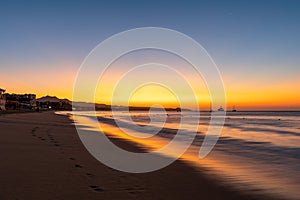 A vibrant sunrise with light reflecting in waves on the coastline of Cabo San Lucas