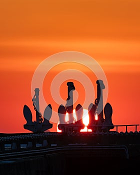 Vibrant sunset over Ontario Place marina - silhouettes of the 3 anchors of old freighters used for the breakwater