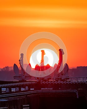 Vibrant sunset over Ontario Place marina in Toronto with silhouettes of the 3 anchors of decommissioned old Great Lakes freighters