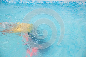 Vibrant swimwear visible in a serene underwater scene in a blue-tiled pool