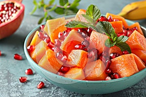 Vibrant tropical fruit salad ingredients on green backdrop for healthy bowl of mixed fruits