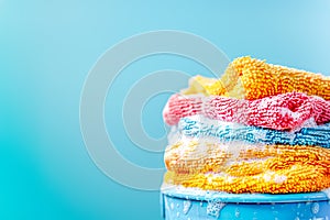 Vibrant, wet utility cloths in suds atop bucket on blue background