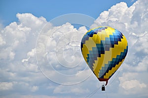 Vibrant yellow and blue hot air balloon is being suspended in the sky by a thin white string