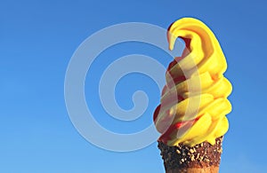 Vibrant Yellow Fruity Flavored Soft Serve Ice Cream Cone Against Sunny Vivid Blue Sky