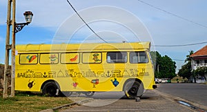 Vibrant yellow skin tourist bus parked on Galle fort, colorful drawings on the bus body