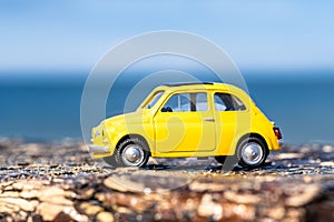 Vibrant yellow toy car parked on a beach.