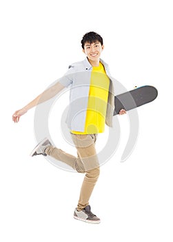 Vibrant young man holding a skateboard and walking