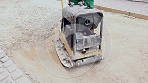 Vibrating machine is compacting soil at the construction site.