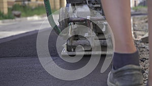 Vibratory asphalt paving machine on the sidewalk filmed close-up.Road works,pavement repair,hard work.Video clip.