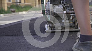 Vibratory asphalt paving machine on the sidewalk filmed close-up.Road works,pavement repair,hard work.Video clip