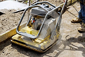 Vibratory plate compactor on a new pavement in a industrial construction machine