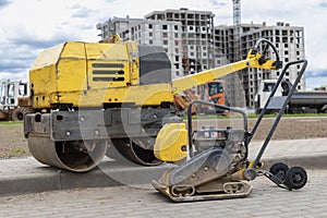 Vibratory rammer with vibrating plate on a construction site. Manual roller. Compaction of the soil before laying paving slabs.