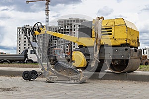 Vibratory rammer with vibrating plate on a construction site. Manual roller. Compaction of the soil before laying paving slabs.