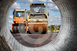 Vibratory road roller lays asphalt on a new road under construction. Close-up of the work of road construction equipment. Modern