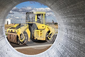 Vibratory road roller lays asphalt on a new road under construction. Close-up of the work of road construction equipment. Modern