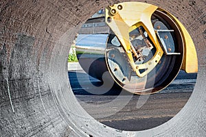 Vibratory road roller lays asphalt on a new road under construction. Close-up of the work of road construction equipment. Modern