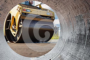 Vibratory road roller lays asphalt on a new road under construction. Close-up of the work of road construction equipment. Modern