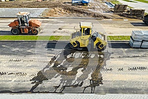 Vibratory road roller lays asphalt on a new road under construction. Close-up of the work of road machinery. view from above.