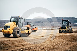 Vibratory Soil Compactors on highway construction site. Industrial roadworks with heavy-duty machinery