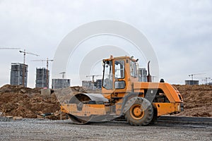 Vibro Roller Soil Compactor leveling soil at construction site. Excavator and vibration single-cylinder road roller