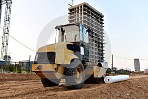 Vibro Roller Soil Compactor leveling soil at construction site. Excavator and vibration single-cylinder road roller during the