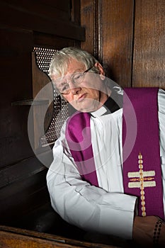 Vicar in confession booth photo