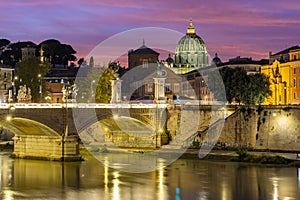 Victor Emmanuel bridge over Tiber river with St. Peter`s cathedral dome in Vatican at night, Rome, Italy